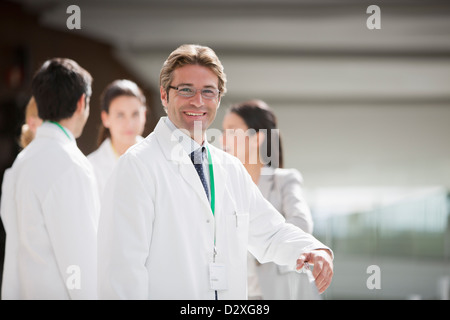 Ritratto di uno scienziato sorridente con i collaboratori in background Foto Stock