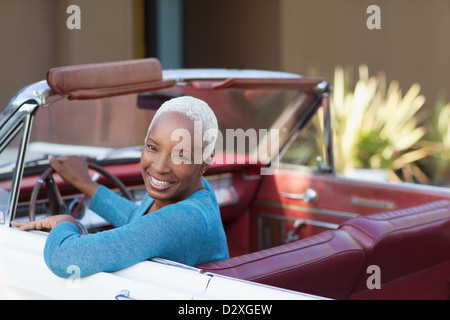 Sorridente donna anziana convertibile di guida Foto Stock