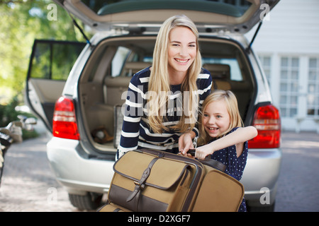 Madre e figlia che trasportano bagagli per auto Foto Stock