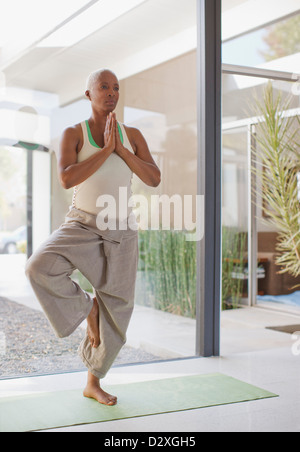 Donna anziana a praticare yoga in casa Foto Stock