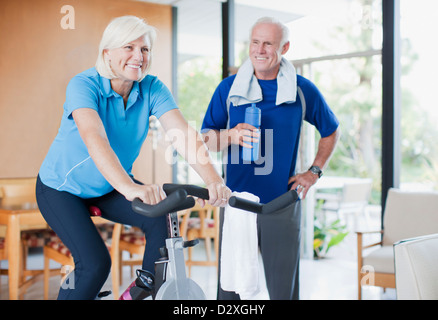 Donna anziana riding cyclette a casa Foto Stock