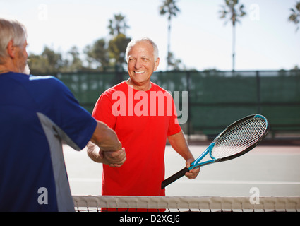 Gli uomini più anziani si stringono la mano sul campo da tennis Foto Stock