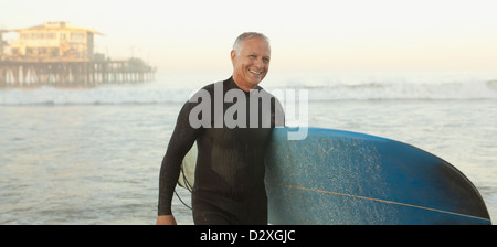 I vecchi surfer scheda portante sulla spiaggia Foto Stock