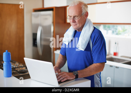 Uomo anziano utilizzando laptop dopo allenamento Foto Stock