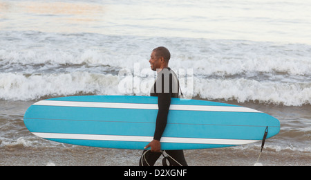 I vecchi surfer scheda portante sulla spiaggia Foto Stock