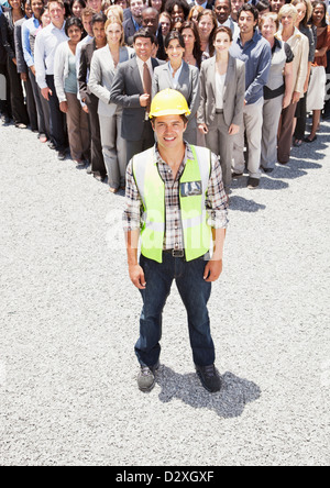 Ritratto di sorridere lavoratore edile con la gente di affari in background Foto Stock