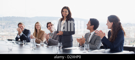 Co-lavoratori battimani per imprenditrice in sala conferenze Foto Stock