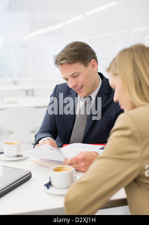 Imprenditore e imprenditrice rivedendo la documentazione presso il ristorante Foto Stock