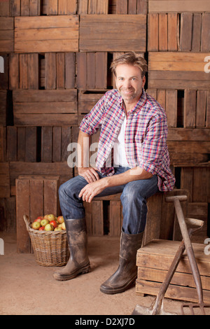 Ritratto di uomo sorridente seduto accanto a staio di mele Foto Stock