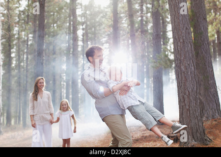 La famiglia felice giocando nella soleggiata boschi Foto Stock