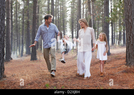 La famiglia felice tenendo le mani e camminare nei boschi Foto Stock