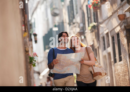 Coppia sorridente con mappa su strada stretta a Venezia Foto Stock