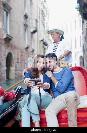 Coppia sorridente tenendo autoritratto con fotocamera digitale in gondola sul Canal a Venezia Foto Stock