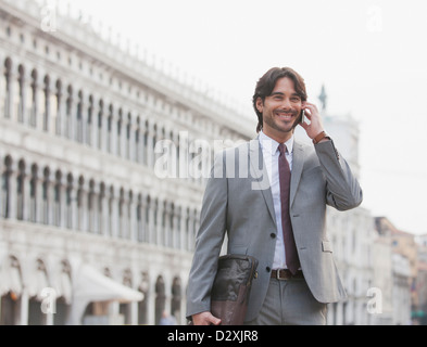 Imprenditore sorridente parlando al cellulare in Piazza San Marco a Venezia Foto Stock