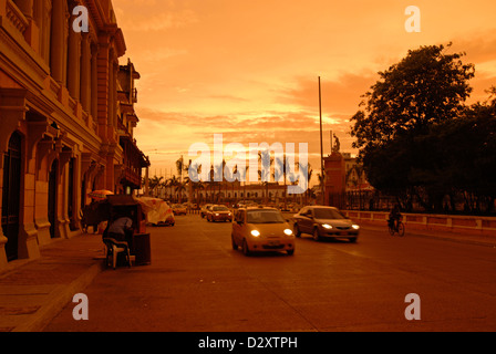 La Colombia, Cartagena, stagliano visualizzazione delle persone sul palm tree road con la Puerta del Reloj al tramonto Foto Stock