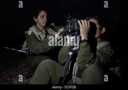 Una soldato israeliana dal Battaglione di intelligenza del campo Eitam del 727th del corpo di raccolta di intelligenza di combattimento usando un Binocolo visione notturna durante l'addestramento avanzato di notte vicino al confine con l'Egitto nel deserto meridionale di Negev Israele Foto Stock