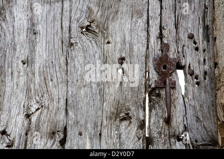 Vecchia porta di legno con serratura metallica e maniglia, è bullet foro danni e il legno ha girato e argenteo incrinato. Foto Stock