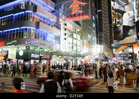 People shopping in Hong Kong con neon via segni di notte Foto Stock
