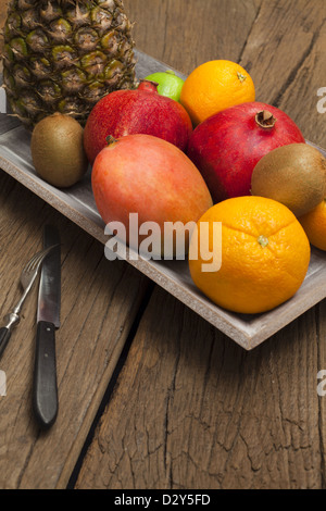 Ciotola di legno con frutta e un coltello con la forcella su un vecchio tavolo in legno Foto Stock