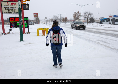 Donna che indossa uno zaino camminando lungo la 8th street nella tempesta di neve Saskatoon Saskatchewan Canada Foto Stock