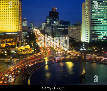 Indonesia, Java, Giacarta, vista serale del Centro di Jakarta con Hotel Indonesia rotonda e trafficata Jalan M.H. Thamrin Foto Stock