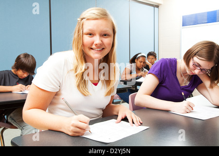Bella ragazza bionda seduta nella sua scuola di alta classe. Foto Stock