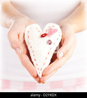Foto del giocattolo morbido a forma di cuore in mani femminili, bella mano presente per il giorno di San Valentino, vacanza romantica, 14 febbraio Foto Stock