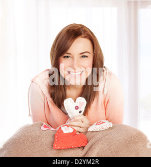 Foto di bella femmina felice seduti a casa in camera da letto con graziosi cuori fatti a mano giocattolo morbido, simbolo dell'amore, omaggio romantico Foto Stock