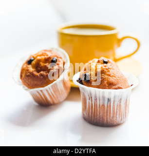 Il caffè in una tazza di colore giallo e muffin Foto Stock
