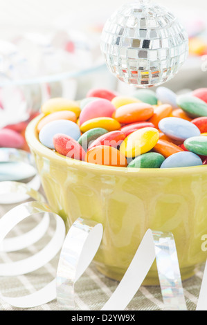 Close up multicolore di caramelle con stelle filanti e miniatura palla da discoteca Foto Stock