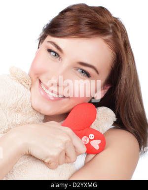 Foto di Pretty Woman abbraccio simpatico giocattolo morbido, closeup ritratto della bella bruna femmina con Teddy bear e rosso cuore fatti a mano Foto Stock