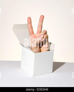 Mano che saltano fuori dalla scatola che mostra segni di pace Foto Stock