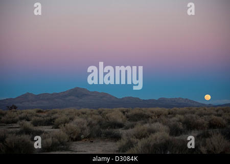 Kramer Junction, California - la luna piena sorge su Fremont picco nel deserto di Mojave. Foto Stock