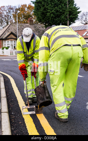 I lavoratori stradali che stabilisce le doppie linee gialla della segnaletica stradale su una strada, REGNO UNITO Foto Stock