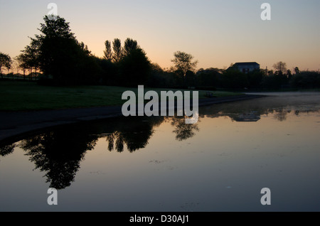 Sunrise behnd stagno in Alexandra Park a Glasgow, Scozia Foto Stock