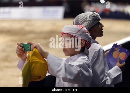 Dubai, Emirati arabi uniti, ragazzo in costume nazionale prende una foto con il suo telefono cellulare Foto Stock