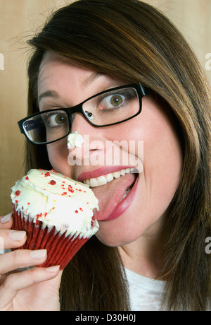 Una donna di mangiare un velluto rosso cupcake Foto Stock