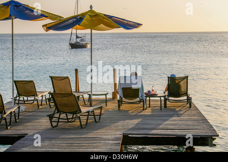 Matura in seduta sdraio su una tavola di legno boatdeck rilassarsi e godersi il tramonto Foto Stock