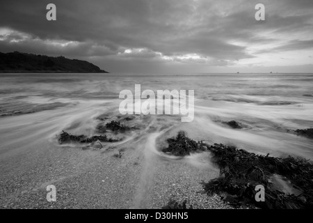 Wave correre indietro al mare sulla spiaggia di Castello in Falmouth di sunrise Foto Stock