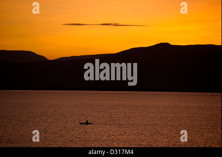 Fisherman paddling una tradizionale barca sul lago Baringo al tramonto, Kenya Foto Stock