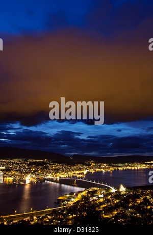Alta Vista aerea su Tromso di notte - nuvole incandescente al della città, riflettendo le luci della città. Foto Stock