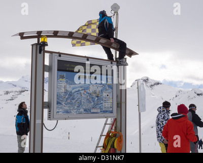 Gli sciatori da pista di mappa e un pisteur modifica Allarme valanga bandiera al livello di rischio 3 in Le Grand Massif ski area nelle Alpi francesi Foto Stock