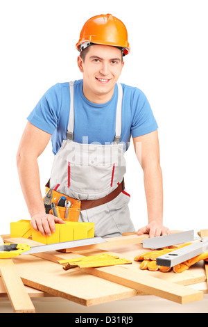 Lavoratore manuale in piedi accanto ad un tavolo con attrezzature e pezzi di legno isolato su sfondo bianco Foto Stock