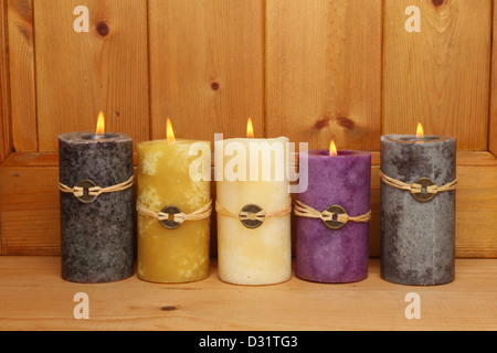 Cinque masterizzazione di Feng Shui candele contro un pannello di legno Foto Stock