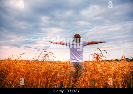 Giovane uomo che soggiornano con stese le mani al tramonto Foto Stock