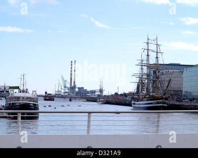 Barche sul fiume Liffey a Dublino Irlanda come si vede dal Samuel Beckett Bridge con le torri gemelle a distanza Foto Stock