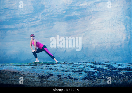 La donna caucasica stretching sulle formazioni rocciose Foto Stock