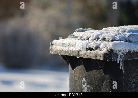 Un bidone della spazzatura lasciata fuori nella neve non riscosse dal Consiglio a causa di pericolose condizioni stradali e la mancanza di attenzione da parte del Consiglio gritter Foto Stock