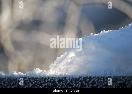 Una chiusura di un grumo di neve su un gelo coperta la superficie nera con una profondità di campo e sfondo interessante il tono freddo Foto Stock