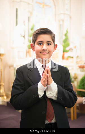 Ragazzo ispanica con le mani incrociate nella chiesa Foto Stock